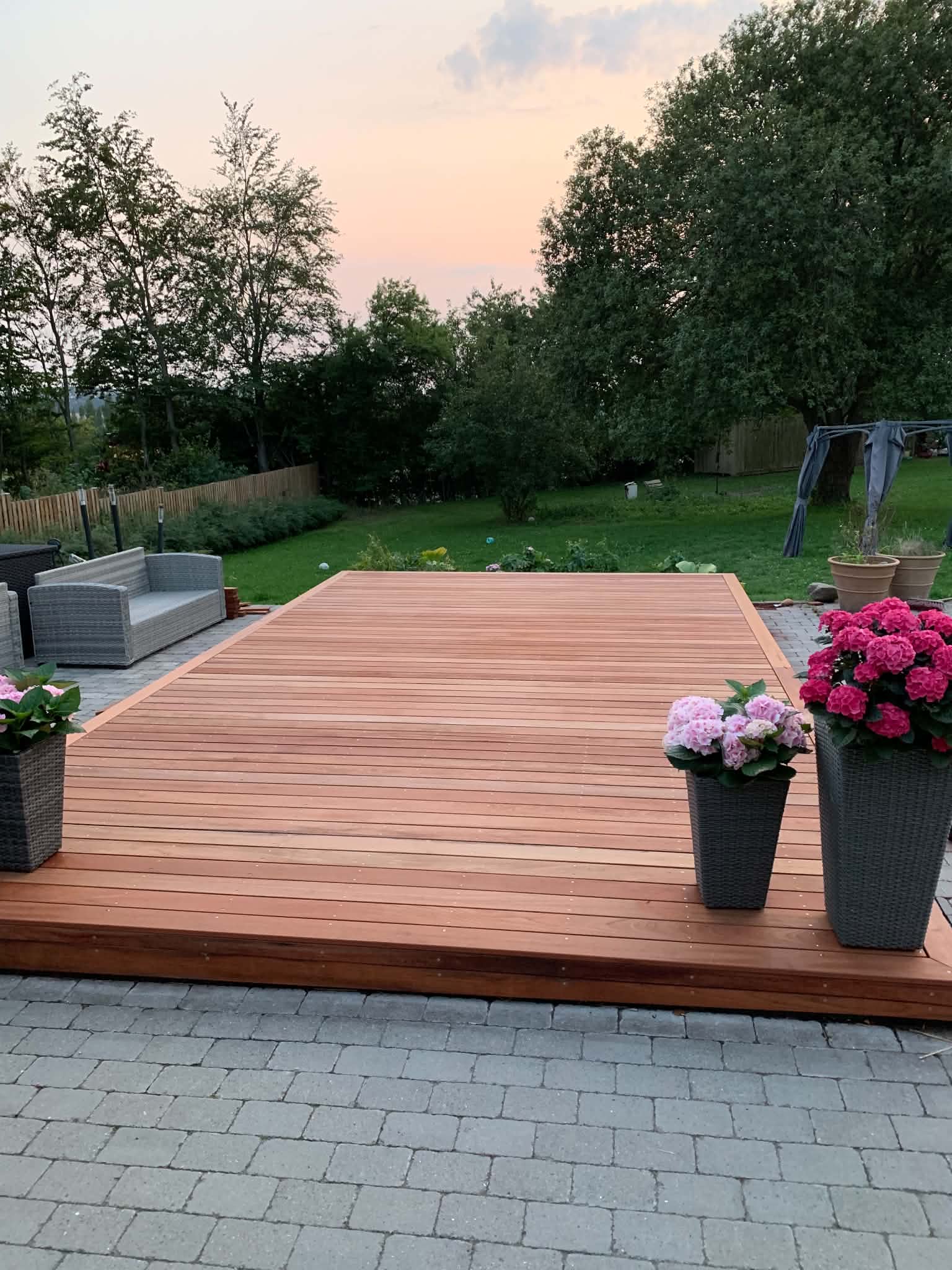 Færdig terrasse i hårdttræ i haven ved solnedgang